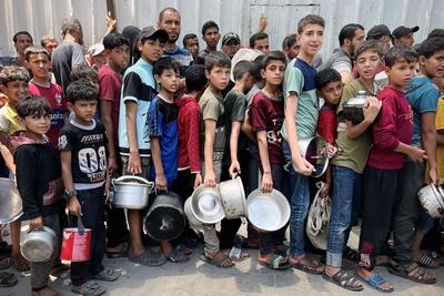Internally displaced Palestinians gather in a charity kitchen to receive limited rations amid a shortage of food-stock-foto