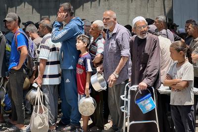 Internally displaced Palestinians gather in a charity kitchen to receive limited rations amid a shortage of food-stock-foto