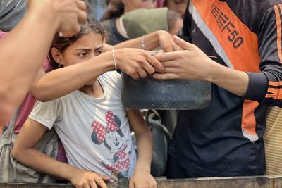 Internally displaced Palestinians gather in a charity kitchen to receive limited rations amid a shortage of food-stock-foto