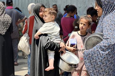 Internally displaced Palestinians gather in a charity kitchen to receive limited rations amid a shortage of food-stock-foto