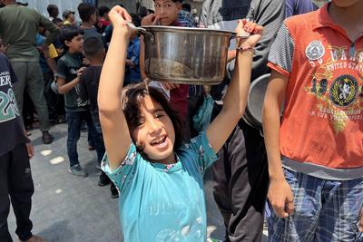 Internally displaced Palestinians gather in a charity kitchen to receive limited rations amid a shortage of food-stock-foto