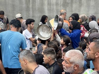 Internally displaced Palestinians gather in a charity kitchen to receive limited rations amid a shortage of food-stock-foto