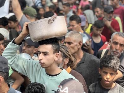 Internally displaced Palestinians gather in a charity kitchen to receive limited rations amid a shortage of food-stock-foto