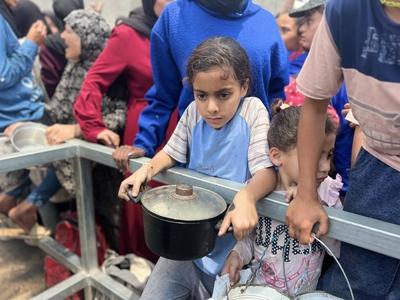 Internally displaced Palestinians gather in a charity kitchen to receive limited rations amid a shortage of food-stock-foto