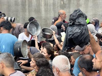 Internally displaced Palestinians gather in a charity kitchen to receive limited rations amid a shortage of food-stock-foto
