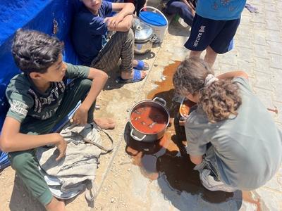 Internally displaced Palestinians gather in a charity kitchen to receive limited rations amid a shortage of food-stock-foto