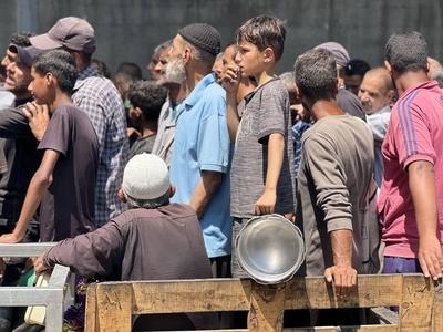 Internally displaced Palestinians gather in a charity kitchen to receive limited rations amid a shortage of food-stock-foto