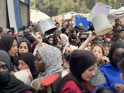 Internally displaced Palestinians gather in a charity kitchen to receive limited rations amid a shortage of food-stock-foto
