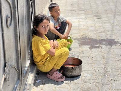 Internally displaced Palestinians gather in a charity kitchen to receive limited rations amid a shortage of food-stock-foto