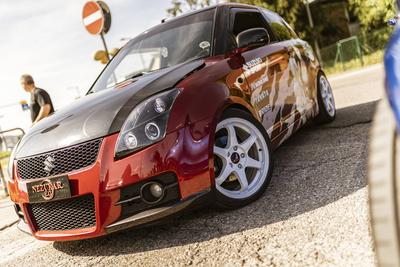 Rome, italy 4 may 2025: tuned red suzuki swift with carbon fiber hood, aftermarket rims and custom livery parked on asph-stock-foto