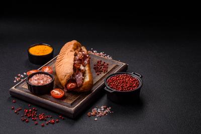Leckerer saftiger Hot Dog mit Wurst, Speck, So?e, Salz und Gew?rzen-stock-foto