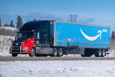 Banff, Alberta, Kanada. 2. Apr. 2025. Ein Amazon Prime-Sattelschlepper mit einem hellblauen Anh?nger f?hrt auf einem verschneiten Highway unter einem klaren Himmel.-stock-photo
