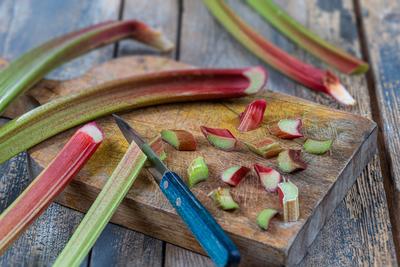Rhubarb, vegetable plant Close-up of rhubarb cut into small pieces with a knife on a cutting board. Copyright: xCHASSENE-stock-foto