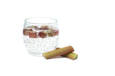 Glass of water with rhubarb pieces over white Transparent glass filled with cold water and several pieces of rhubarb iso-stock-foto