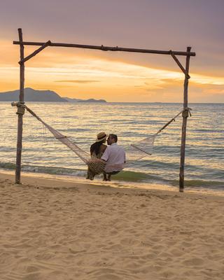 Men and women watching sunset from a hammock on the beach in Pattaya Thailand Ban Amphur beach Men and women are watchin-stock-foto