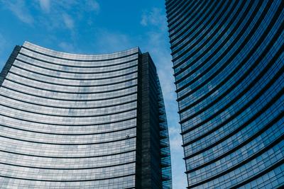 Mailand, Italien - 31.08.2022: Piazza Gae Aulenti. Moderne urbane Architektur mit geschwungenen Glasfassaden, die den blauen Himmel im Stadtbild reflektieren-stock-foto