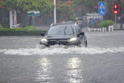 DONGFANG, CHINA - JUNE 14: A car drives through flooded street following the impact of Typhoon Wutip on June 14, 2025 in-stock-photo