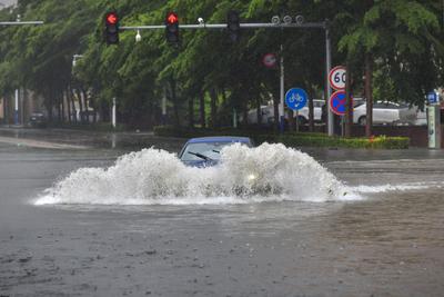 DONGFANG, CHINA - JUNE 14: A car drives through flooded street following the impact of Typhoon Wutip on June 14, 2025 in-stock-photo