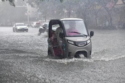 DONGFANG, CHINA - JUNE 14: An electric tricycle drives through flooded street following the impact of Typhoon Wutip on J-stock-photo