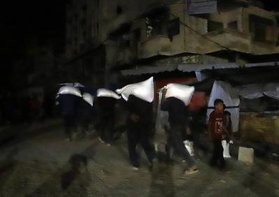 People carry their sacks of flour Flour they got from aid trucks in North Gaza Strip, where there is a food crisis due to Israeli attacks-stock-foto