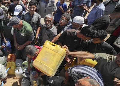 Palestinians carry jerry cans filled with water distributed by a water tanker-stock-foto
