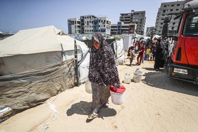 Palestinians carry jerry cans filled with water distributed by a water tanker-stock-foto