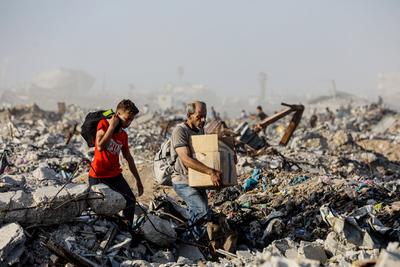Palestinians carry food parcel, distributed by 'Gaza Humanitarian Relief Foundation' as people struggle with hunger during ongoing Israeli attacks in Gaza City-stock-foto