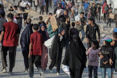 Palestinians carry food parcel, distributed by 'Gaza Humanitarian Relief Foundation' as people struggle with hunger during ongoing Israeli attacks in Gaza City-stock-foto