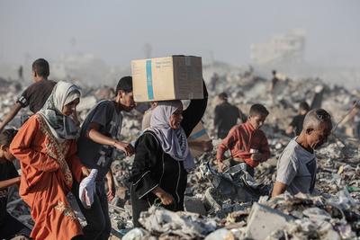 Palestinians carry food parcel, distributed by 'Gaza Humanitarian Relief Foundation' as people struggle with hunger during ongoing Israeli attacks in Gaza City-stock-foto