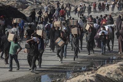 Palestinians carry food parcel, distributed by 'Gaza Humanitarian Relief Foundation' as people struggle with hunger during ongoing Israeli attacks in Gaza City-stock-foto