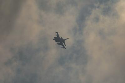An Israeli fighter jet flies overhead as people rush towards an truck carrying humanitarian aid in western Jabalia-stock-foto