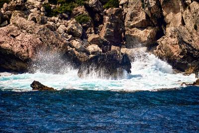 Menorca, Spain - June 13, 2025: Huge waves off Menorca crash against jagged rocks on a rocky coast, while spray splashes-stock-photo
