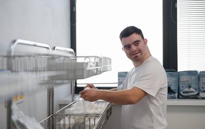 Young man with down syndome working in hospital as orderly. Concept of integration people with disability into society.-stock-foto