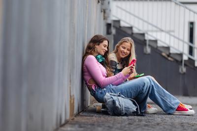 Young stylish generation Z girls spending time outdoors after school. Young stylish generation Z girls spending time out-stock-foto