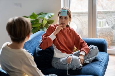 Nachdenklich Teenager-M?dchen nachdenklich erraten Wort auf Aufkleber auf der Stirn spielen mit Freund Spiel, das ich bin-stock-photo