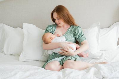 Gl?ckliche Familie zu Hause. Mutter stillt Baby f?r Gesundheit Ern?hrung Wellness. Mutter stillen F?tterung ihr neugeborenes Kind Milch zu Hause. Frau S?ugling M?dchen in wei?en Schlafzimmer Mutter umarmt Baby mit Liebe Pflege.-stock-foto