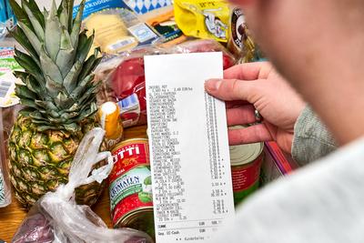 Bavaria, Germany - November 29, 2024: A man holds a shopping list with an amount of over 100 euros for a food purchase.-stock-foto
