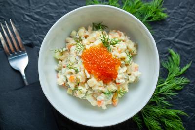 Russischer Salat mit rotem Kaviar und Dill, serviert in einer wei?en Sch?ssel-stock-foto