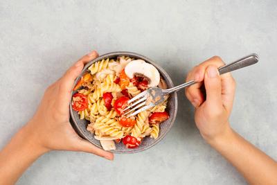 Eating a pasta salad with sliced mushroom, tomato, red pepper pieces and tuna, healthy food with vegetables, fresh organ-stock-photo