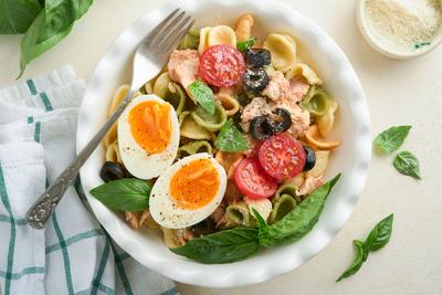 Italienischer Nudelsalat. Orecchiette-Nudeln mit Thunfisch, Kirschtomaten, Oliven, Basilikum und Parmesank?se in einem Teller auf grauem Stein- oder Betonhintergrund. Traditionelle italienische K?che. Flach gelegt. Platz zum Kopieren.-stock-photo