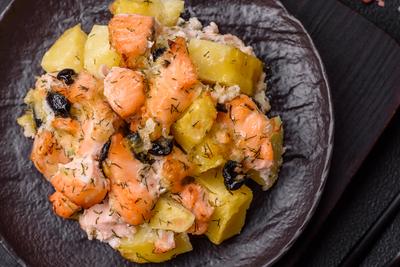 Gebackene Lachsst?cke mit Kartoffeln, K?se und Oliven-stock-foto