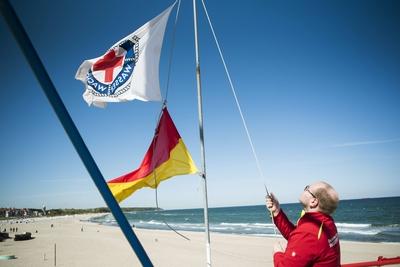 Rettungsschwimmer Lukas Knaup von der DRK Wasserwacht Rostock Warnem?nde zieht die Signalfahne auf-stock-foto