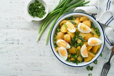 Traditioneller Kartoffelsalat mit Speck und Eiern in einer wei?en Sch?ssel. Picknick-Essen Konzept. Sch?ssel mit warmem Kartoffelsalat. Deutscher Kartoffelsalat. Ansicht von oben.-stock-photo