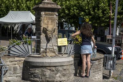 D?rre und knappes Wasser. Eine Junge Frau bef?llt Flaschen aus dem Brunnen Drachenfelsquelle in Bad Honnef. Auf einem Ze-stock-foto