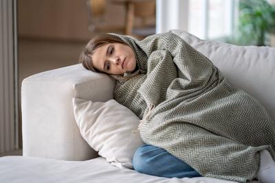Einsame Frau versteckt sich in einer Decke auf dem Sofa, regungslos, ?berw?ltigt von Traurigkeit, Depression und Isolation-stock-foto