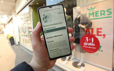 Ein Mann h?lt vor der Filiale des ?sterreichischen Textilherstellers Palmers am Eppendorfer Baum sein Smartphone in der-stock-photo