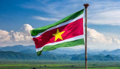 FOTOMONTAGE Die Fahne von Suriname, flattert im Wind, isoliert, gegen den blauen Himmel-stock-photo