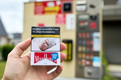 Stettenhofen, Bavaria, Germany - May 28, 2024: Hand holds a pack of Marlboro cigarettes costing 10 euros in front of a c-stock-foto
