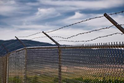 United States of America - June 9, 2024: Security fence and barbed wire in front of a rural landscape, symbolizing borde-stock-foto