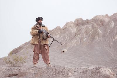 A Taliban soldier stands with a machine gun, In the desert mountain landscape A Taliban soldier stands with a machine gu-stock-foto